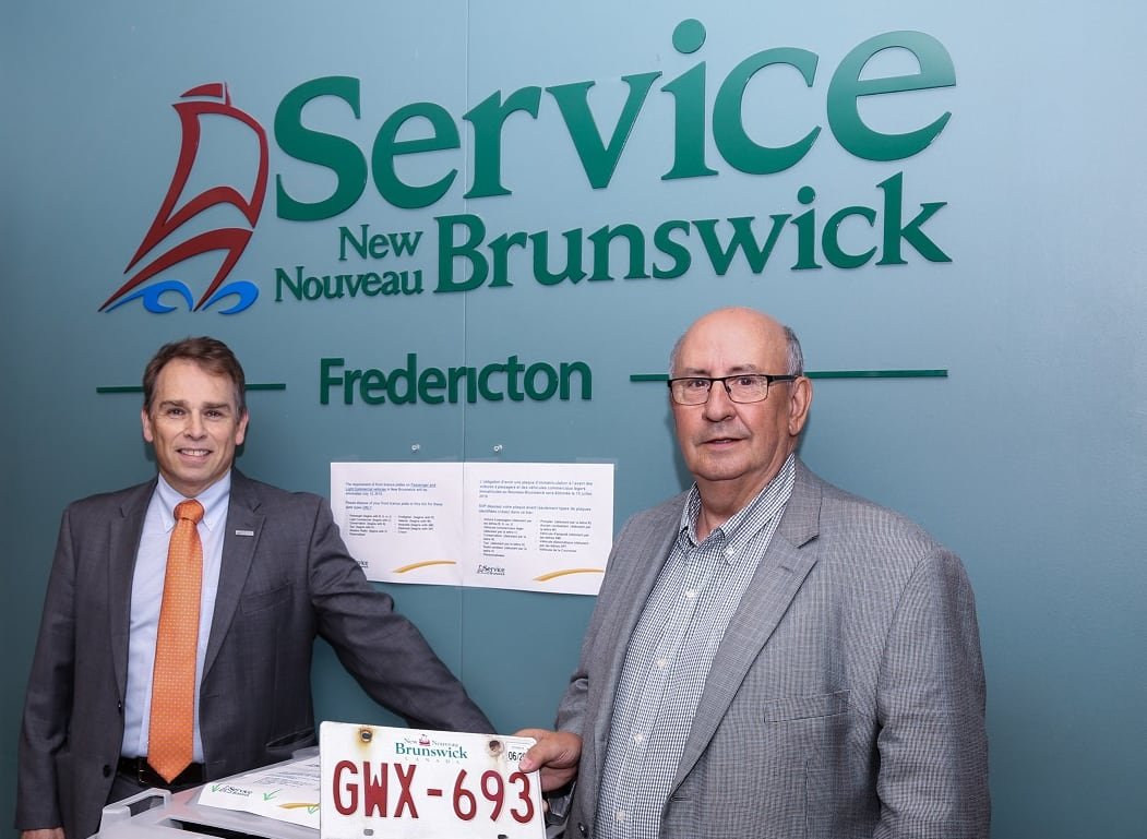 Two individuals holding a license plate