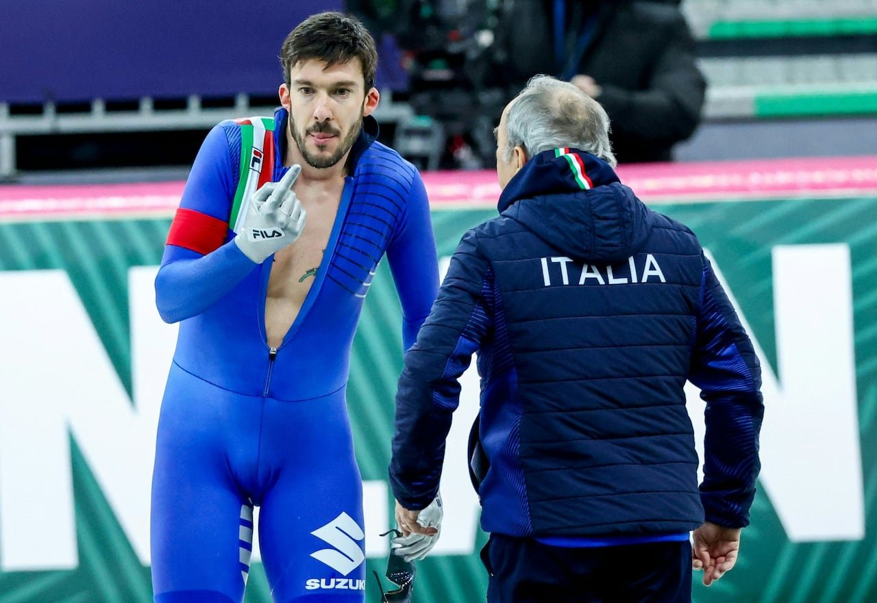 A speed skater speaks with his coach.